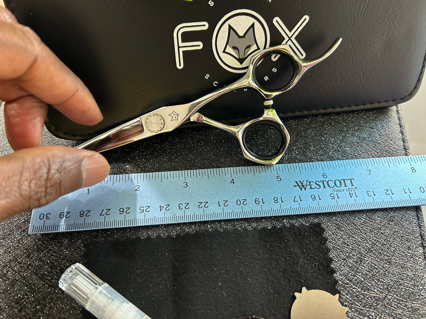 Scissors resting against black case with ruler for scale.