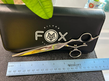 Scissors resting against black case next to ruler for scale.