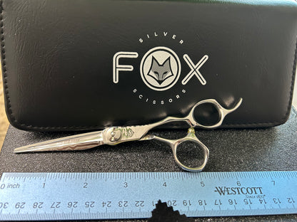 Scissors resting against black case next to ruler for scale.