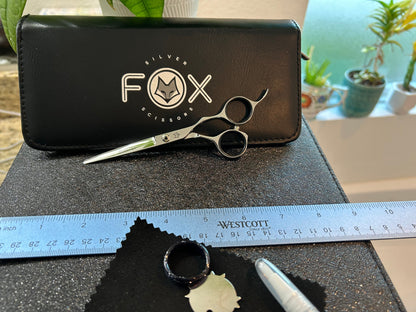 Scissors resting against black case next to ruler.