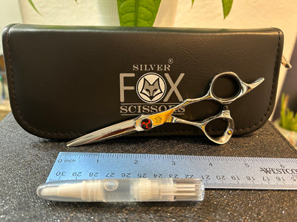 Scissors resting against black case next to ruler for scale.