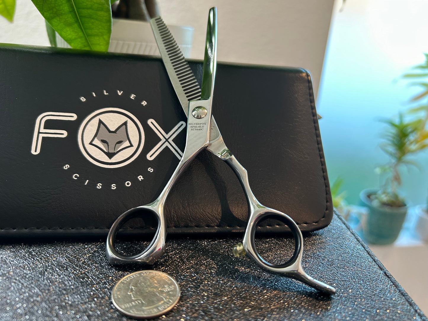 Scissors standing upright against black case with object in front for scale.