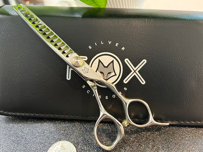 Scissors standing upright against black case with object in front for scale.