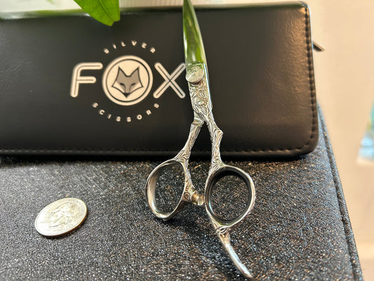 Scissors standing upright against black case with object in front for scale.