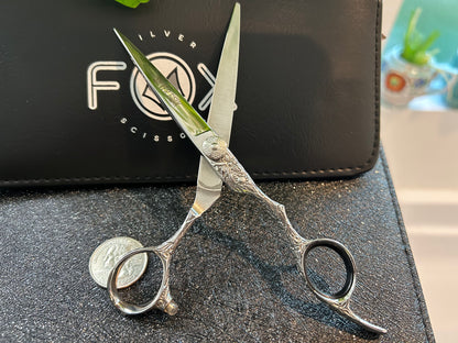 Scissors standing upright against black case with object in front for scale.