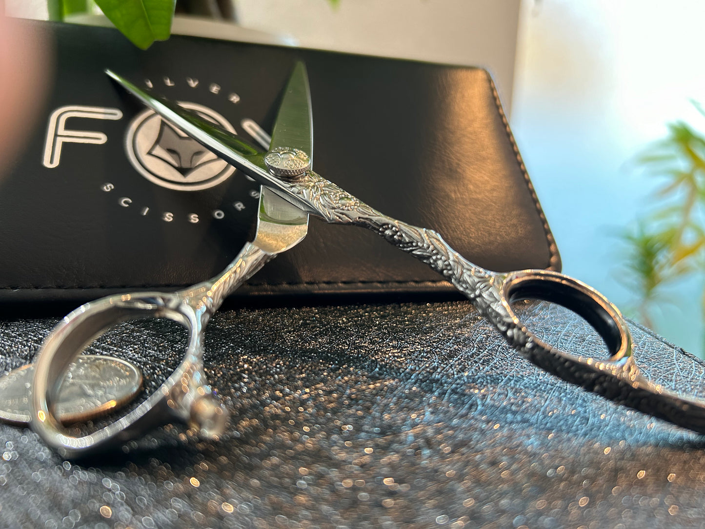 Scissors standing upright against black case with object in front for scale.