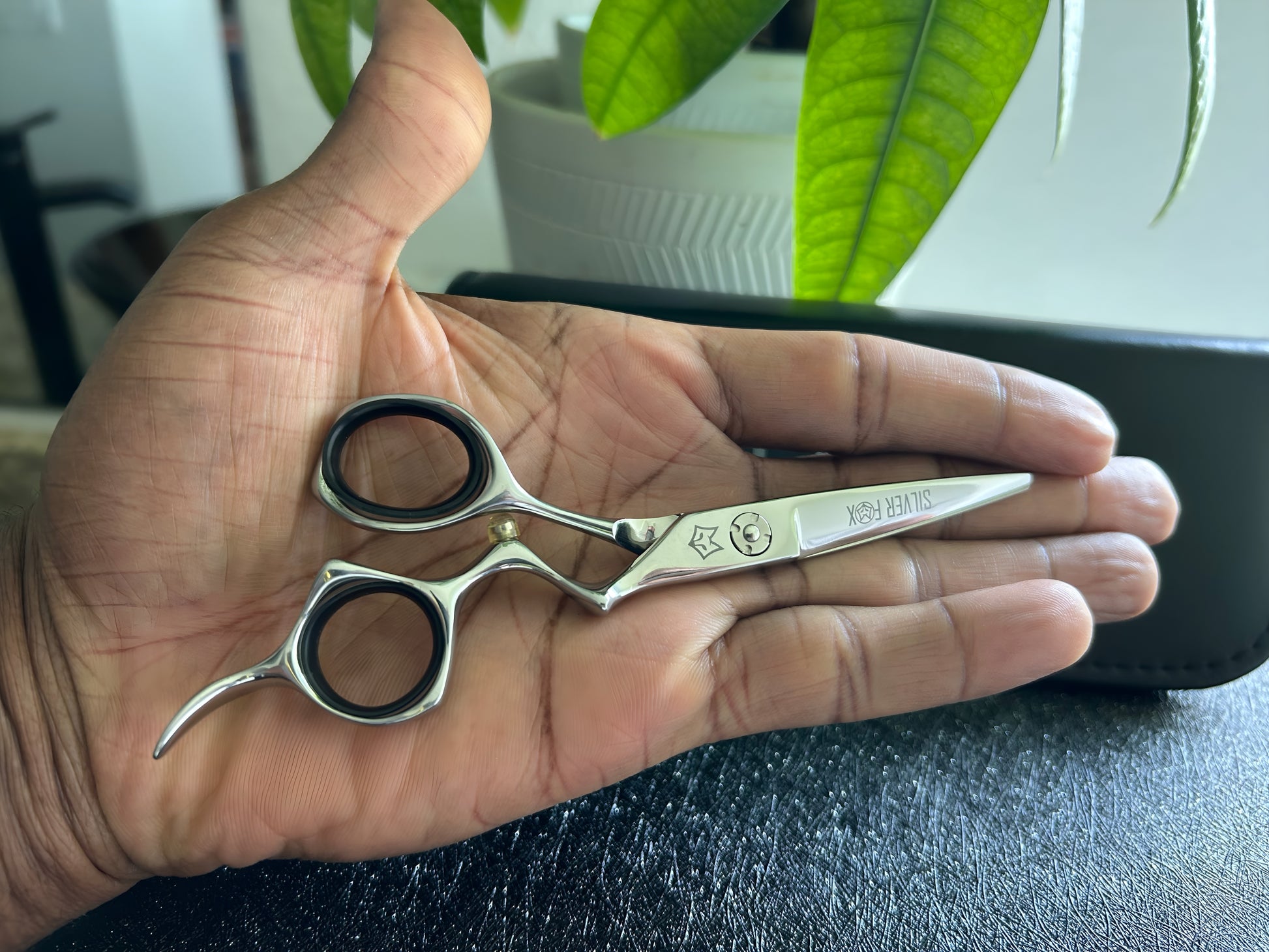 Frontal view of Silver Fox Scissors Model SF28 being held inside the left hand.