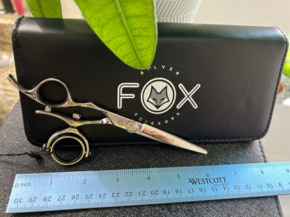 Scissors resting against black case with ruler for scale.