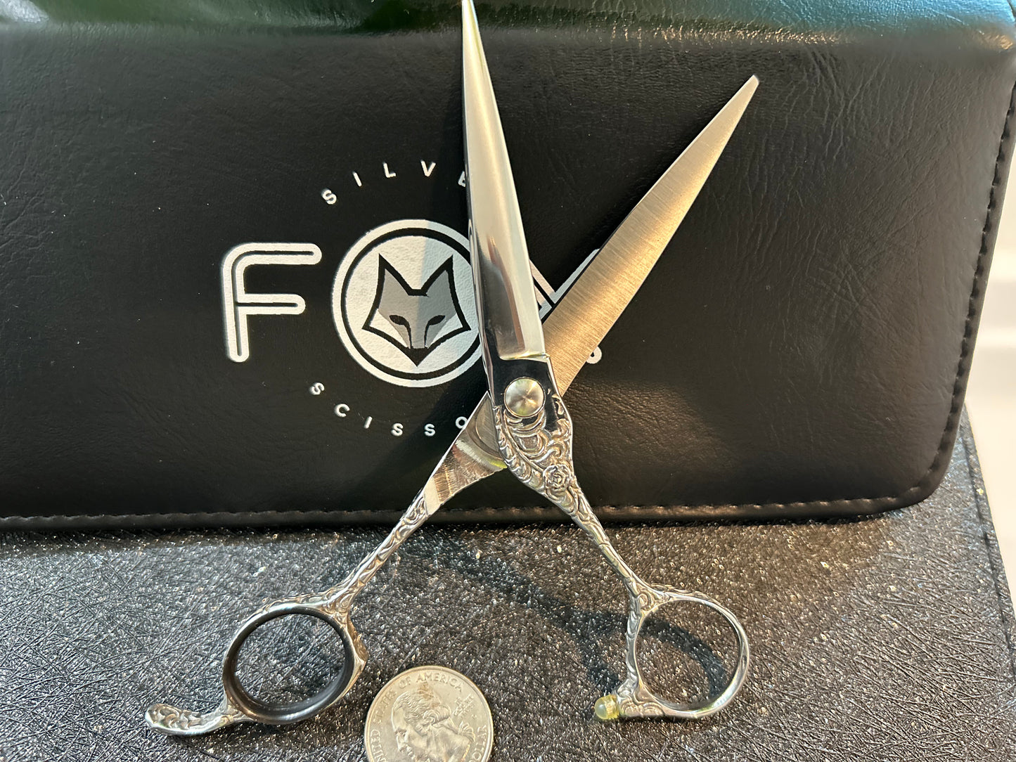 Scissors standing upright against black case with object in front for scale.