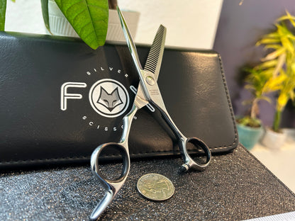 Scissors standing upright against black case with object in front for scale.