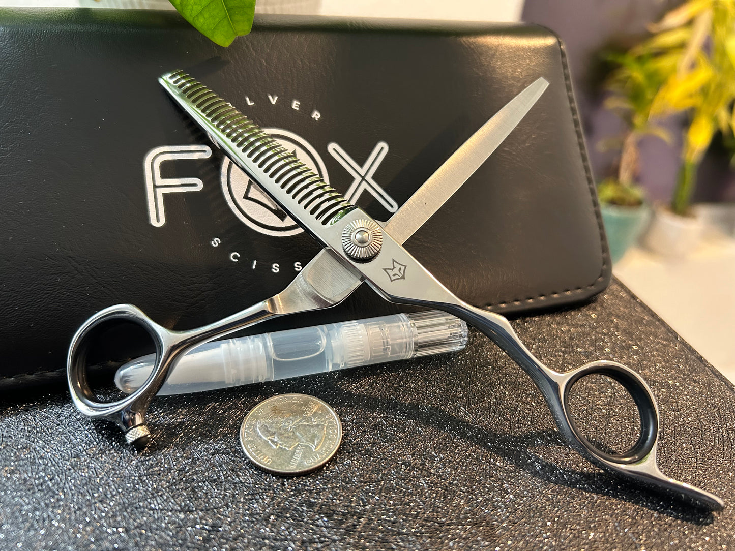 Scissors standing upright against black case with object in front for scale.