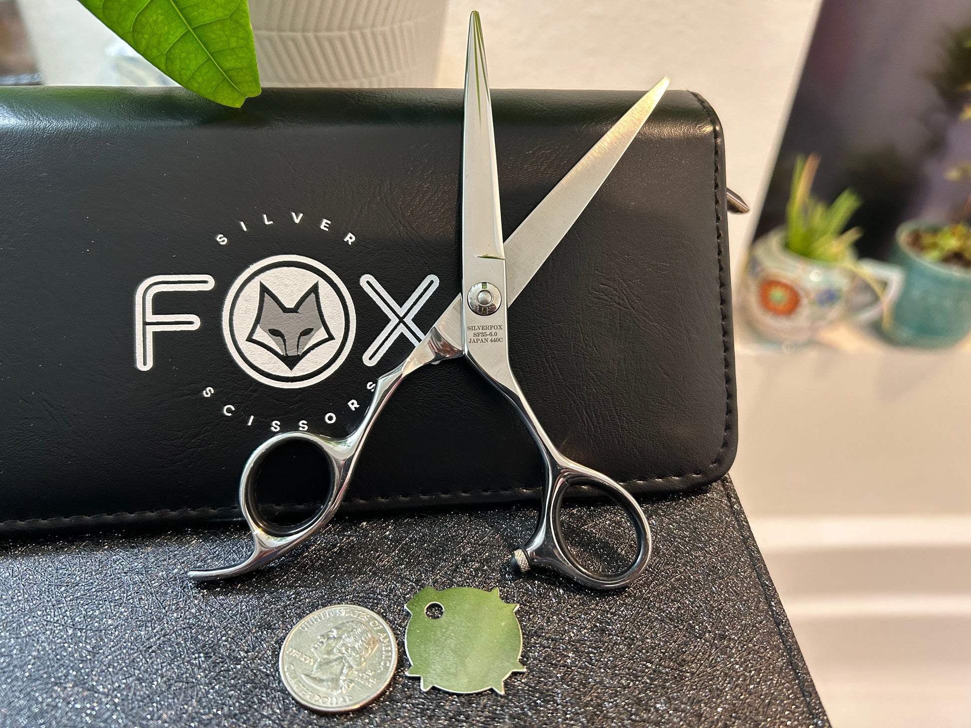 Scissors standing upright against black case with object in front for scale.