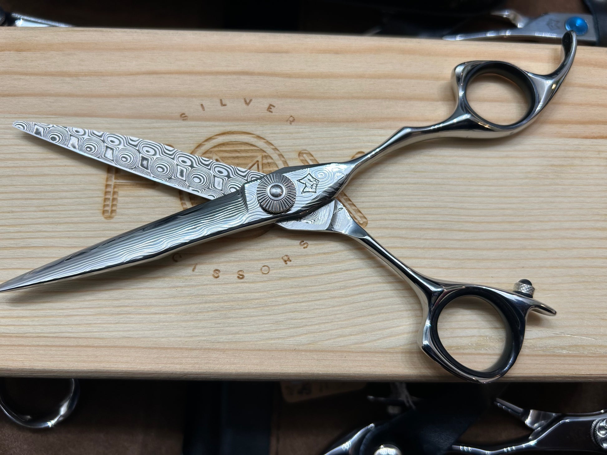 Scissors resting flat in cutting position on top of wooden case.